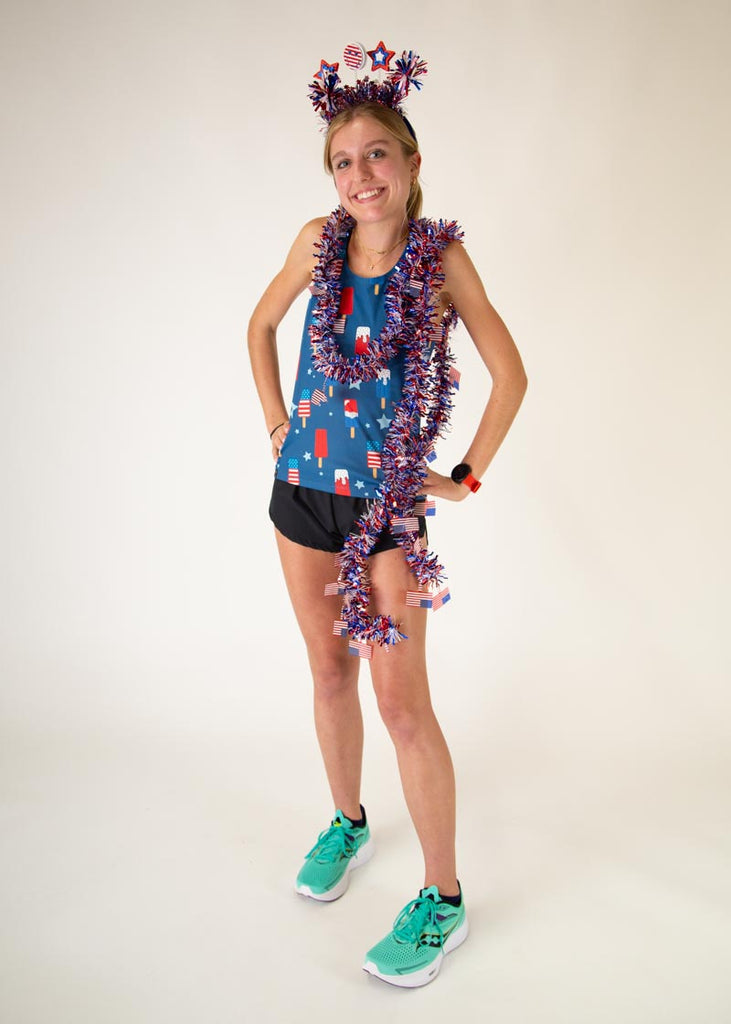 Runner is wearing ChicknLegs in the women's performance singlet in the USA Popsicle singlet. The print has ice cream all over it in red white and blue posing with fun festive american pride.