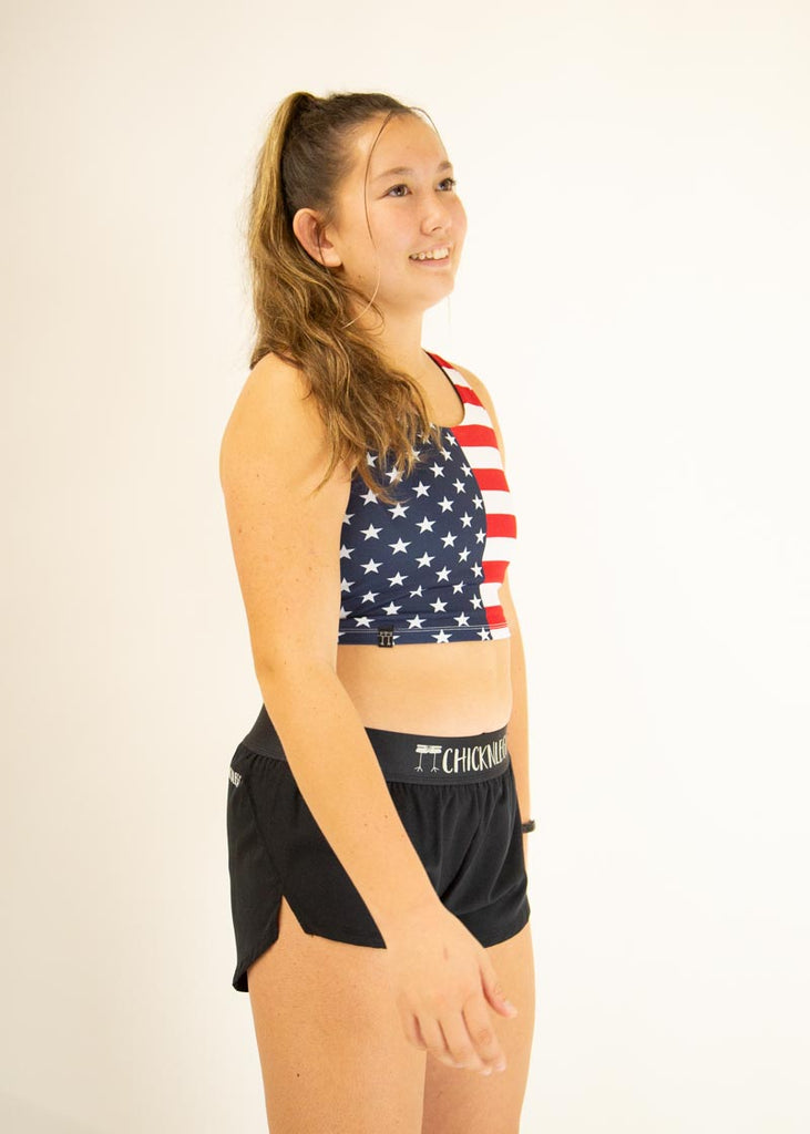 The model is a runner who is wearing Chicknlegs women's pwr USA crop top, facing right.