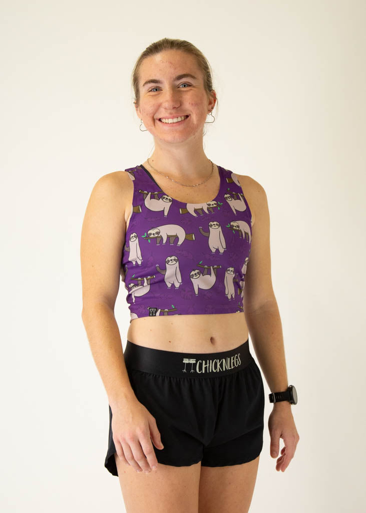 The model is a runner who is wearing Chicknlegs PWR crop top in the sloths design, facing right.