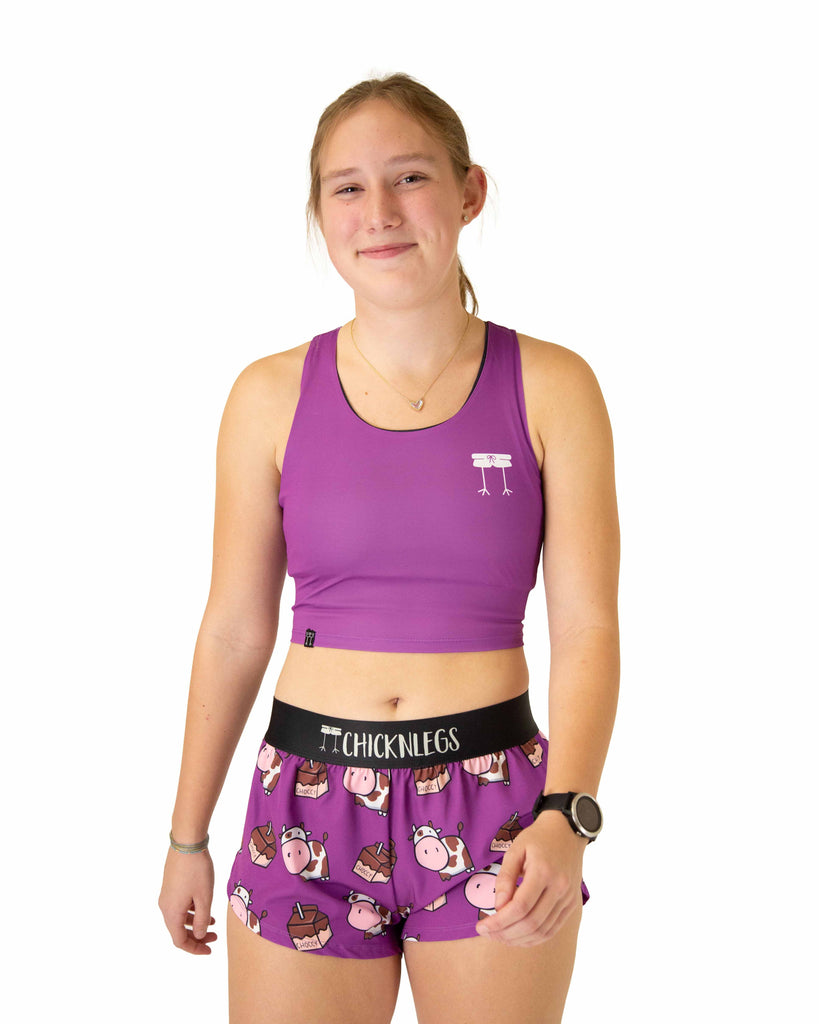Runner is wearing ChicknLegs in the women's power crop top in the deep purple design. The material is lightweight and the print is a solid purple color.