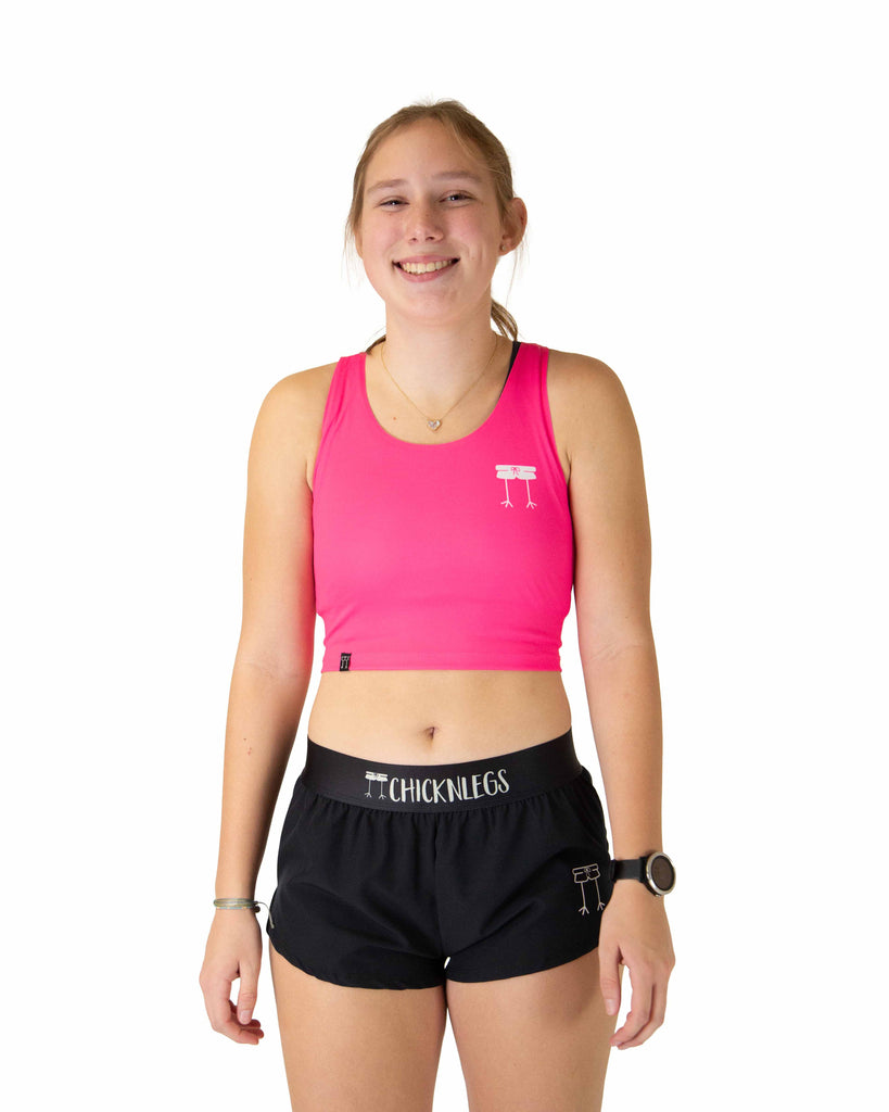 Runner is wearing ChicknLegs in the women's power crop top in the neon pink design. The material is lightweight and the print has a solid neon pink color.