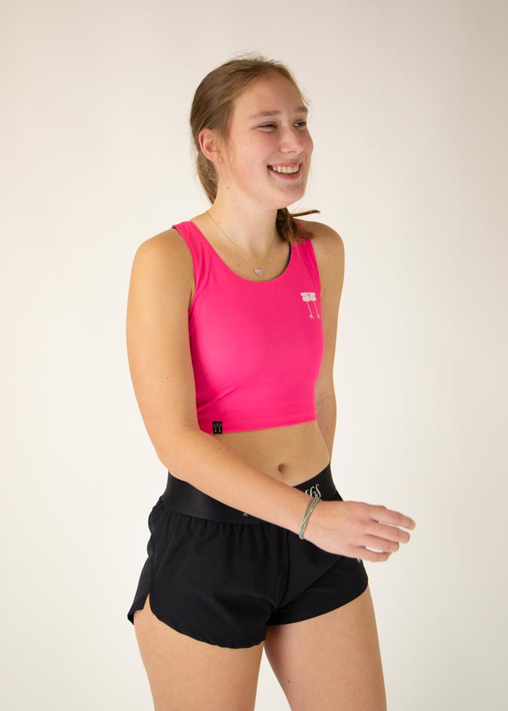 The model is a runner who is wearing Chicknlegs women's Neon Pink pwr crop top, facing right.