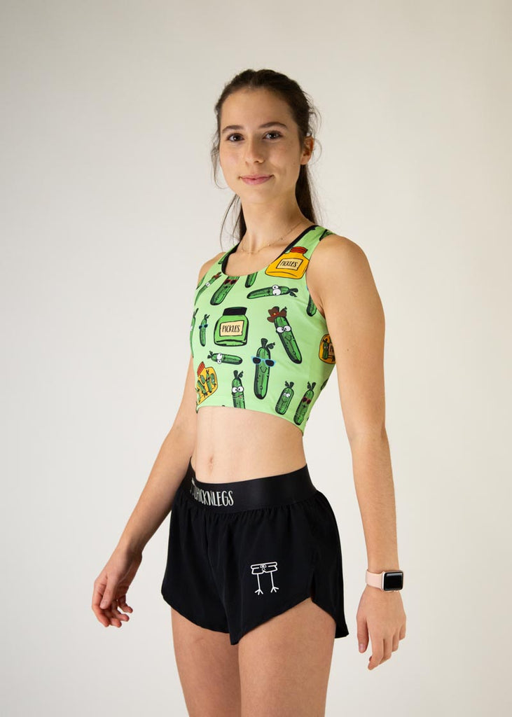The model is a runner who is wearing Chicknlegs in the women's PWR crop top, in the pickles design, facing left.