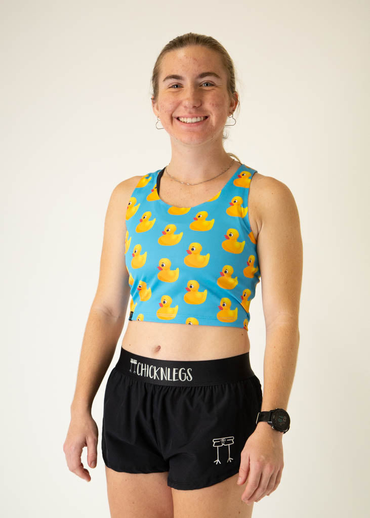 The model is a runner who is wearing Chicknlegs PWR crop top, in the rubber ducky design, facing left.