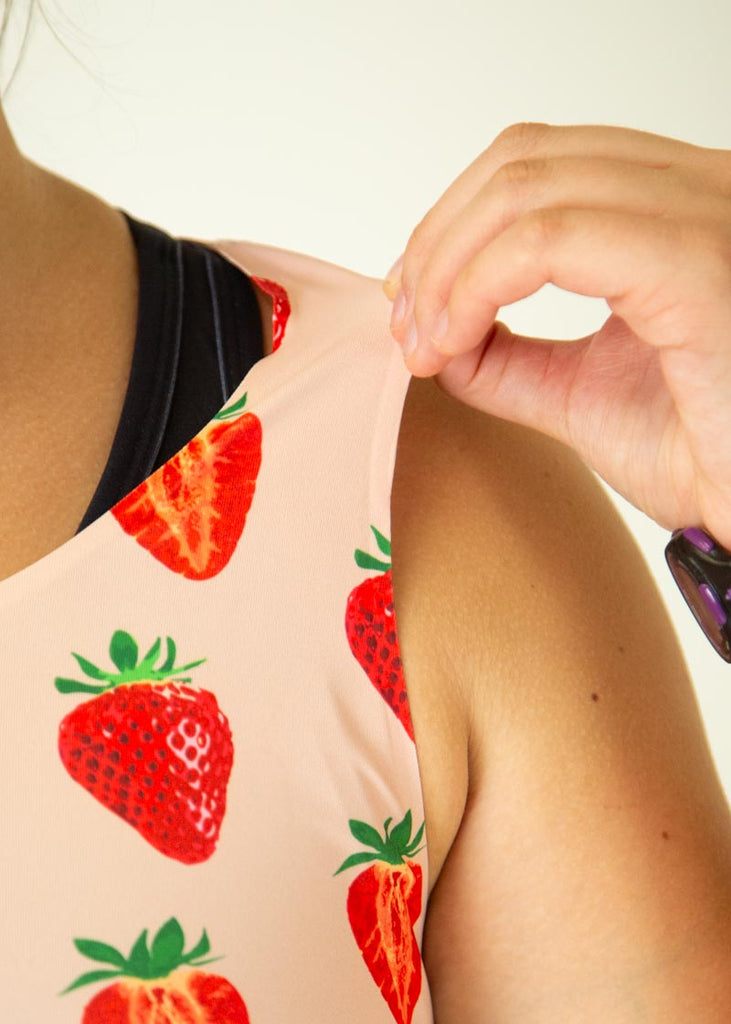 The model is wearing Chicknlegs women's pwr crop top in the strawberry szn design, facing front, a close up is shown to show the thin fabric of the product.