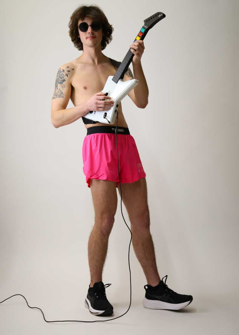Runner playing guitar hero while wearing the men's 4" neon pink running shorts.
