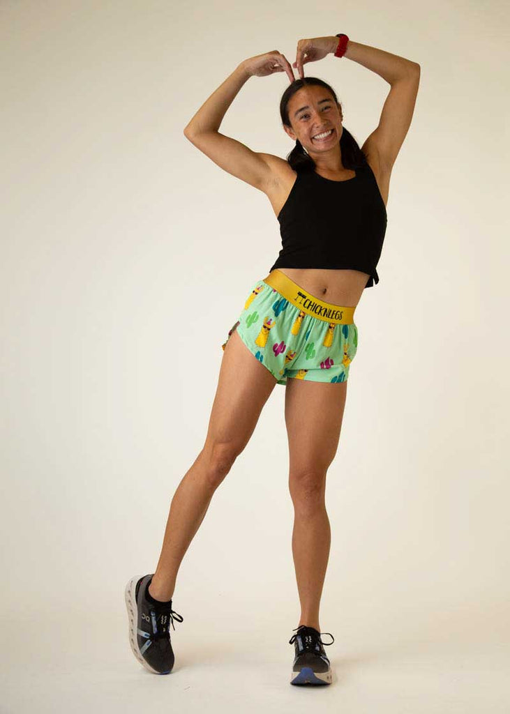 Full body view of the women's green llamas 1.5 inch split running shorts.