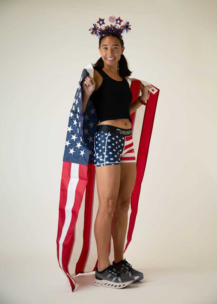 Full body view of the women's 3 inch USA compression running shorts from ChicknLegs holding a bigger USA flag.