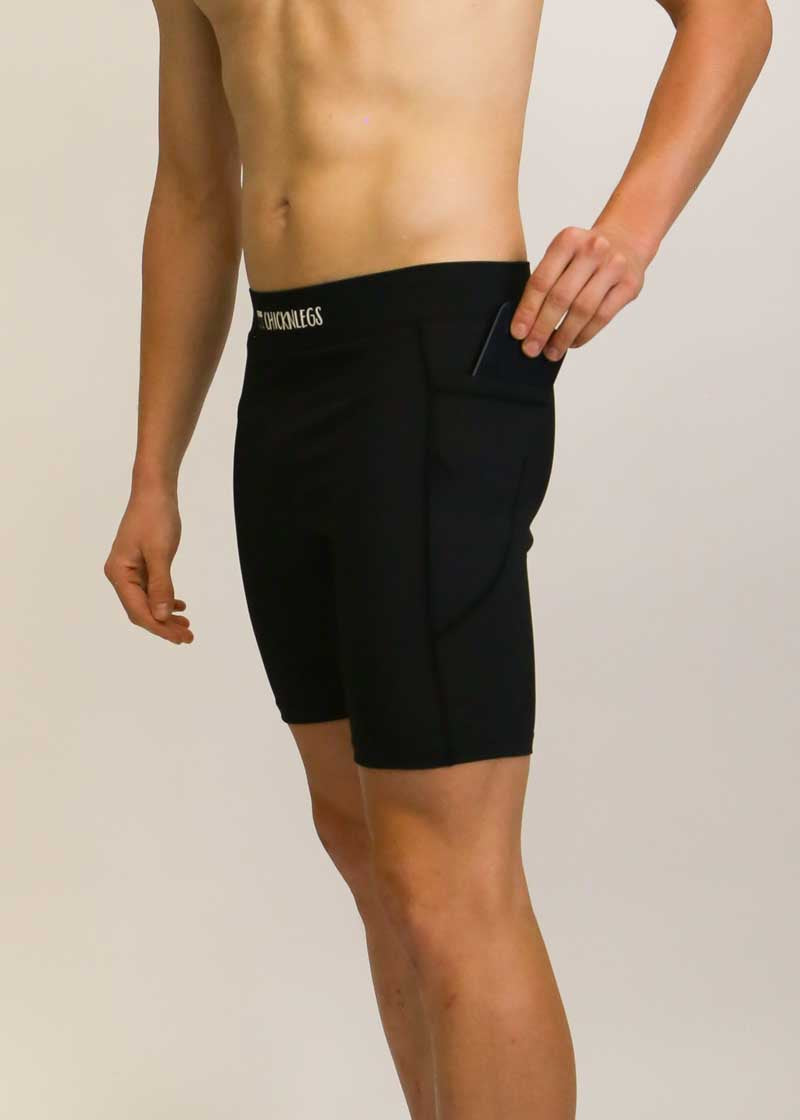 Side view of runner putting phone in the pocket of the black half tights.