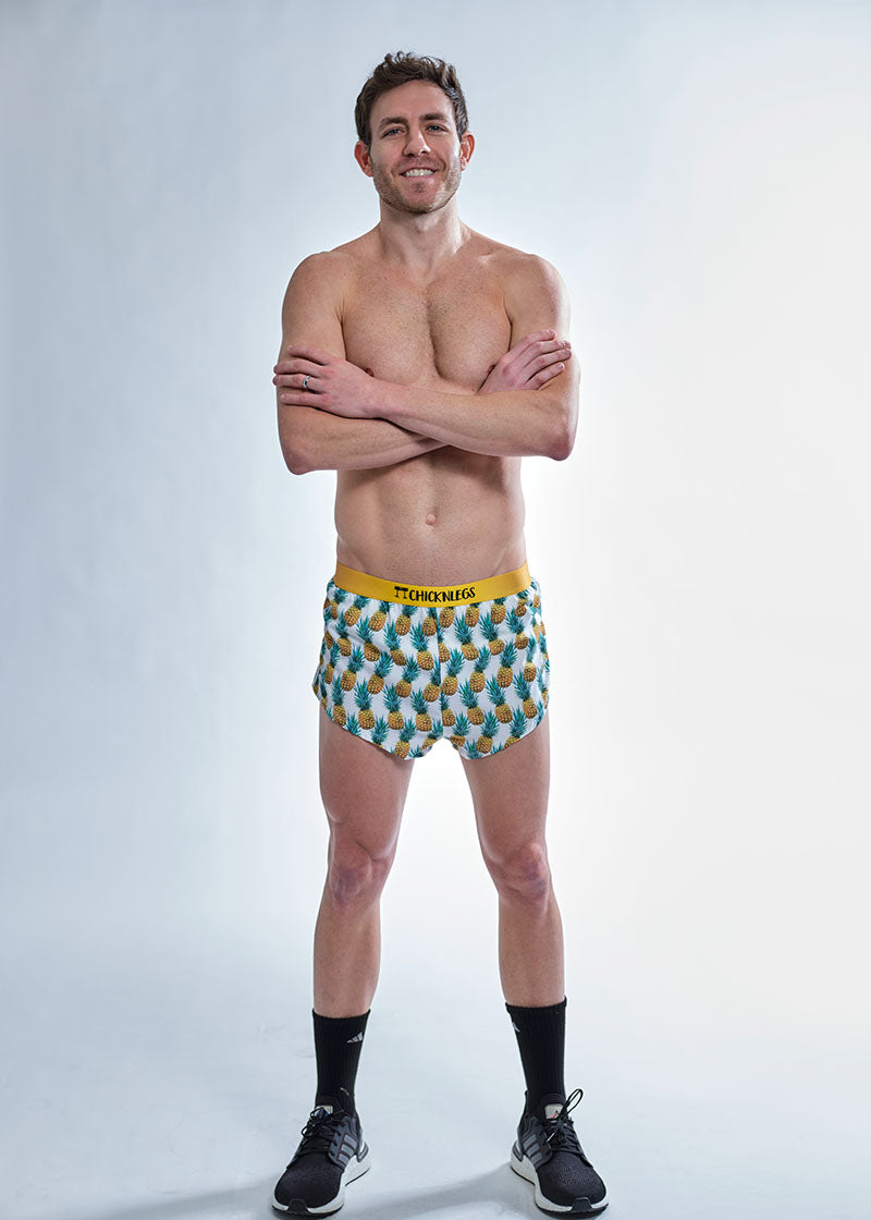 Full body view of the chicknlegs men's trippy pineapples 2 inch split running shorts.