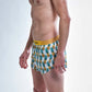 Side logo view of the chicknlegs men's trippy pineapples 2 inch split running shorts.