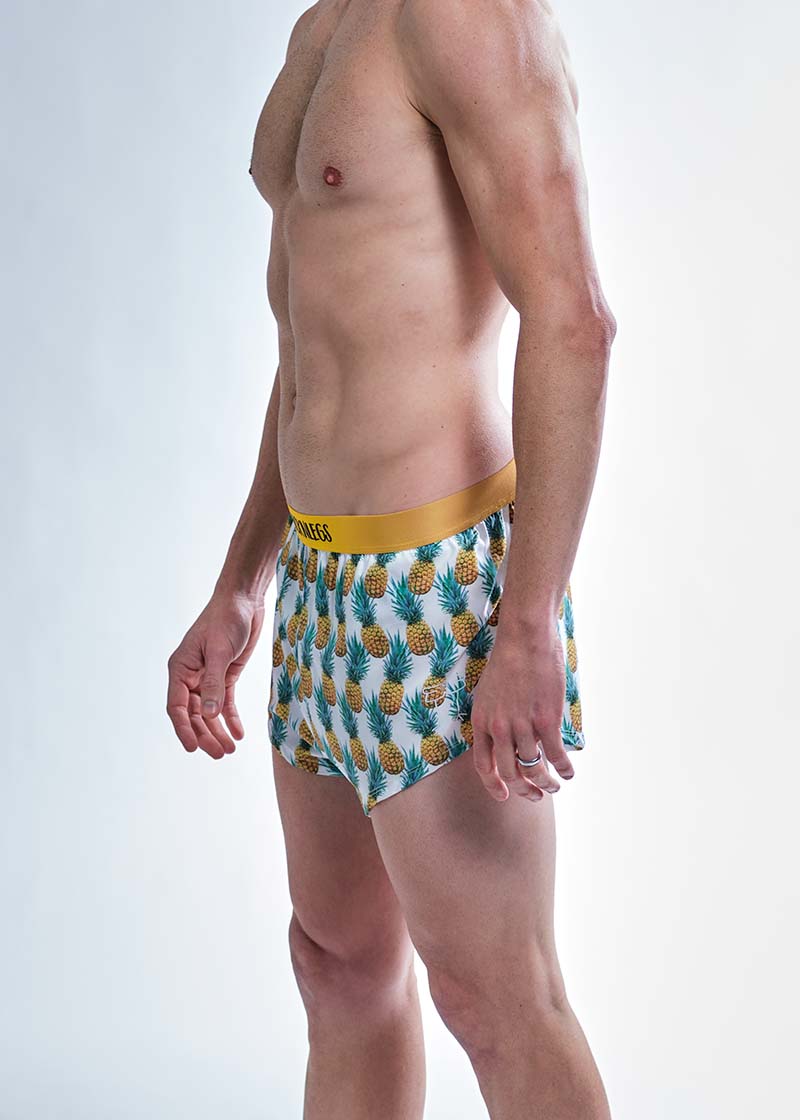 Side logo view of the chicknlegs men's trippy pineapples 2 inch split running shorts.