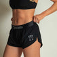 ChicknLegs women's black 1.5" split running shorts side logo view.