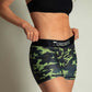 ChicknLegs women's green camo 3 inch compression running shorts front view while holding the waistband.