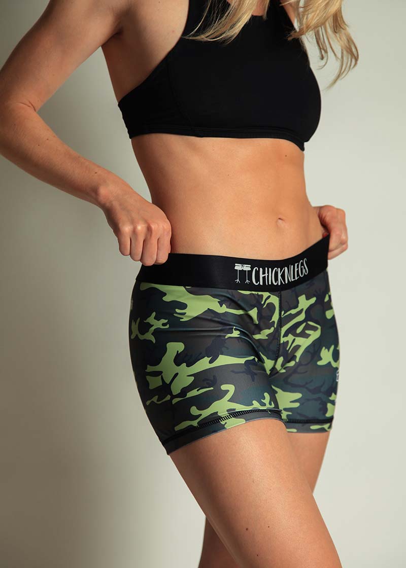 ChicknLegs women's green camo 3 inch compression running shorts front view while holding the waistband.