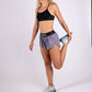 Full body view of model while stretching in the ChicknLegs women's 1.5" heather grey split running shorts.