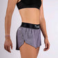 Side closeup view of the ChicknLegs women's 1.5" heather grey split running shorts.