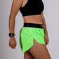 Side closeup view of the ChicknLegs women's neon green 1.5 inch split running shorts.