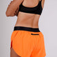 Rear side view with zipper pocket of the women's 1.5 inch neon orange split running shorts.