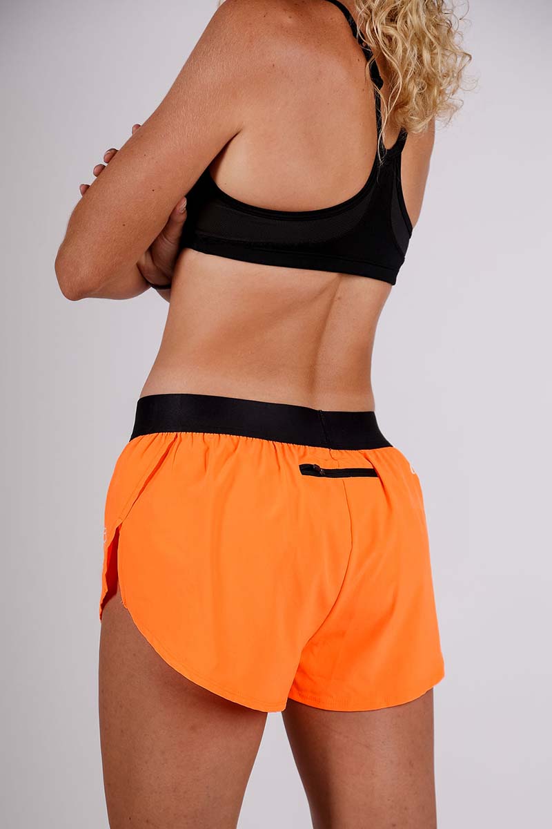Rear side view with zipper pocket of the women's 1.5 inch neon orange split running shorts.