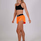 Full body shot from the side of the women's 1.5 inch neon orange split running shorts.