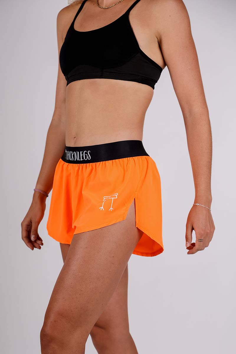 Left side view of the women's 1.5 inch neon orange split running shorts.