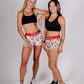 ChicknLegs women's 1.5" pasta night split running shorts group shot with arm on shoulder.