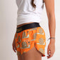ChicknLegs women's snail's pace 1.5" split running shorts side view showing our logo paired with a white tank top.