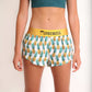 ChicknLegs women's trippy pineapple 1.5" split running shorts front view with green sports bra.