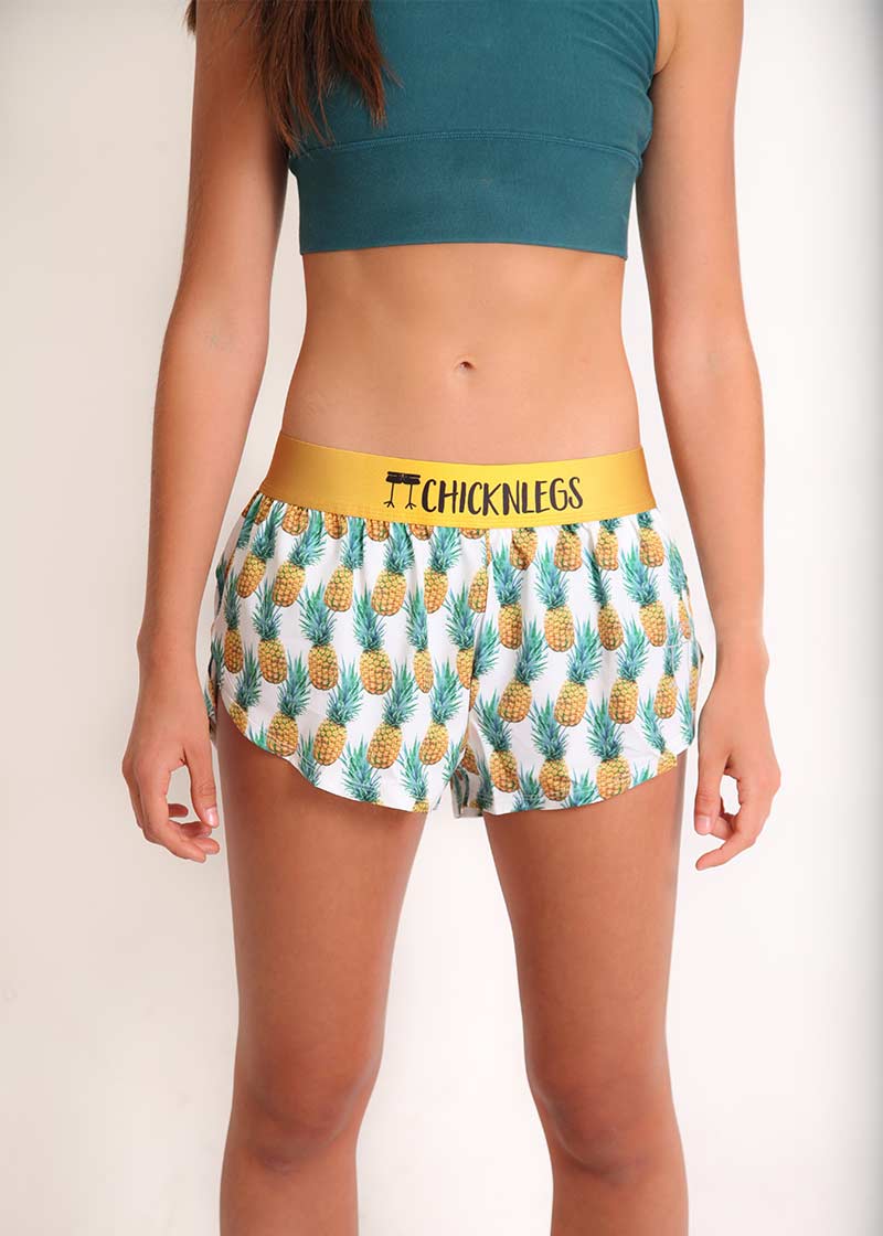 ChicknLegs women's trippy pineapple 1.5" split running shorts front view with green sports bra.